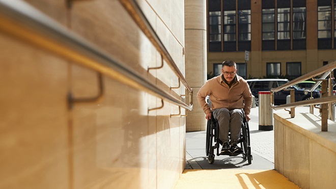 een rolstoelgebruiker aan een gebouw